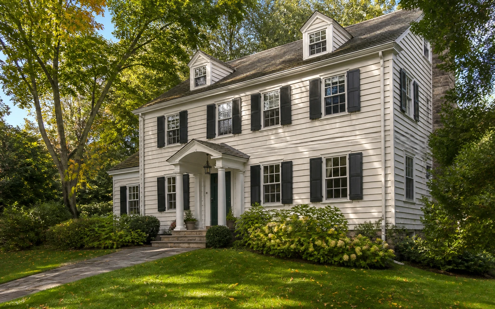 Painted New England Colonial exterior in a leafy residential setting